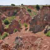 Ci basta per� percorrere qualche metro per ammirare finalmente la cava principale, dall�alto. Il paesaggio � ipnotico: le pareti rosse, valorizzate dal verde della vegetazione e arricchite dall�azzurro del cielo, ci trasportano in un mondo visivamente inedito, dominato da un�incantevole armonia cromatica